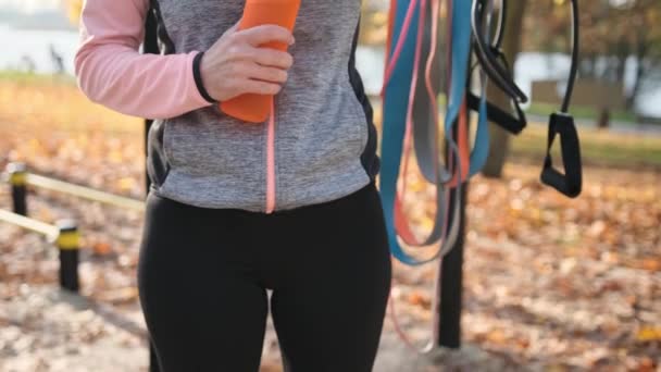 在秋季公园积极锻炼后 健身女孩拿着生态水瓶 女运动员在训练过程中身体水化 — 图库视频影像