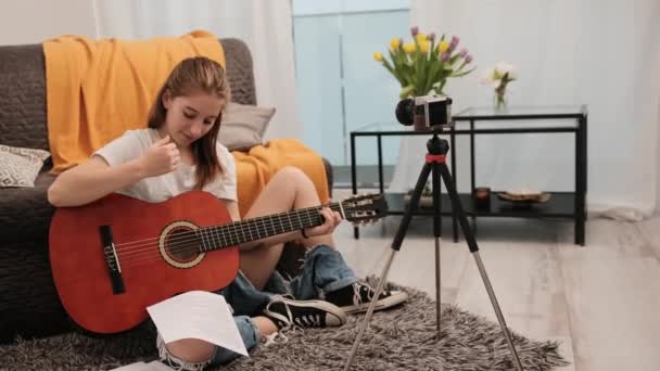 年轻的少女 带着吉他 向追随者们做现场直播 并在网上解释如何演奏乐器 在社交媒体频道摄像的漂亮女吉他手 — 图库视频影像