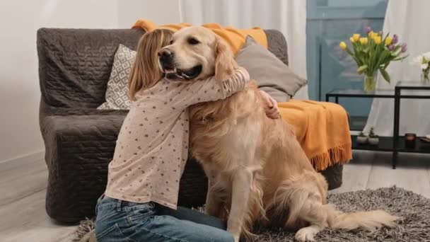 自宅の床に座っているで黄金のレトリバー犬を抱きかかえている十代の女の子の子供 かわいいです女性子供ペットPurebreededペットOggyでリビングルーム — ストック動画