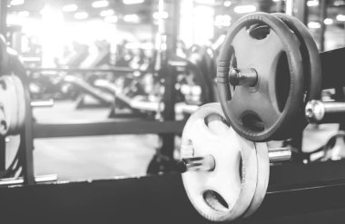Modern bir spor salonunda farklı ağırlıklarla raflar, siyah beyaz çekim
