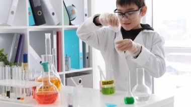 Schoolboy at chemistry lesson working with tubes and equipment for experiments. Pupil boy in lab studying