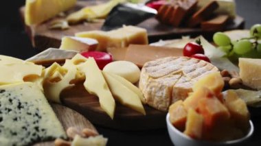 Cheese plate with various cheeses on a dark table.