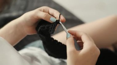 Girl knitting with wool thread homemade warm clothes at home. Traditional handiwork process and craft hobby closeup