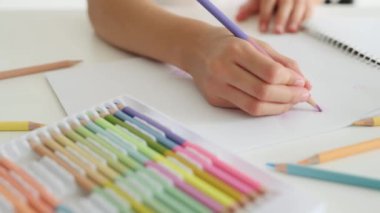 Beyaz kağıda Coloful paletinden boya kalemleriyle çocuk eli çizimi. Albümdeki kalemlerle resim yapan çocuk.