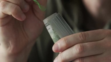 Man holding hundred dollar bills rolled up with rubberband, close up view