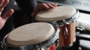 Müzisyen el Bongo Davulları 'nı kapalı mekanda çalıyor. Geleneksel etnik müzik enstrümanına sahip bir adam
