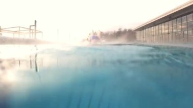 Beautiful girl teenager jumping to pool and swimming under water. Pretty female person diving in blue water