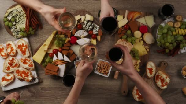 ワインアペタイズとチーズプレート トップビューとテーブル 友人と夕食を楽しみ 赤と白のワインを飲む — ストック動画
