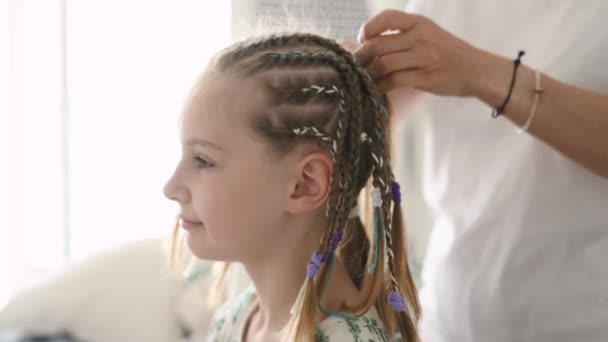 理发师为美发美发的少女在沙龙里编织辫子 时尚染发特写中的理发师手和小孩的情感 — 图库视频影像