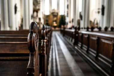 Empty benches in cathedral close up view. Church before the worship.
