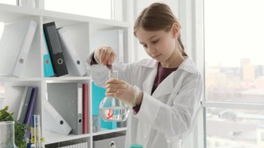 Kimya dersinde kimyasal reaksiyon için su kırmızı sıvısıyla şişeye konan kız öğrenci. Laboratuvarda tüpler ve ekipmanlarla çalışan bir kız öğrenci.