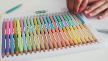 Çocuk eli, Coloful paletinden boya kalemi alır ve beyaz kağıda çizer. Kalemle resim yapan çocuk.