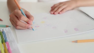 Beyaz kağıda renkli pastel boyayla çocuk eli çizimi. Çocuk parmakları kalem ve resim tutuyor.