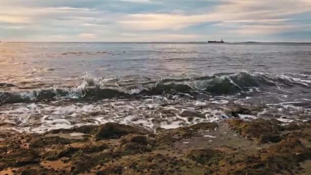 落基海岸有着令人难以置信的日落色的天空和水 海浪和船在地平线上的海滩 — 图库视频影像