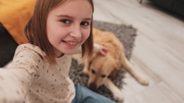 Golden Retriever köpekli küçük kız sosyal medya için video bloğu içeriği kaydediyor. Yavru köpek besleyen güzel bir çocuk çevrimiçi blog videosu çekiyor.