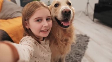 Golden Retriever köpekli küçük kız sosyal medya takipçileri için video bloğu içeriği kaydediyor. Yavru köpek besleyen güzel bir çocuk çevrimiçi blog videosu çekiyor.