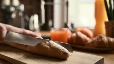 Fransız ekmeğini bıçakla kesen bir kız. Kahvaltı için Fransa 'dan taze ekmek getirdim.