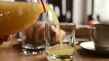 Bir kız mutfakta şişeden bardağa portakal suyu dolduruyor. Evde doğal narenciye içeceği olan bir kadın. Yakın çekim, ağır çekim.