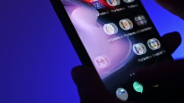 Poznan, Polonya - 13 Ocak: Mavi arka planda uygulamalı akıllı telefon kullanan kız. Sosyal medya uygulaması seçiliyor.