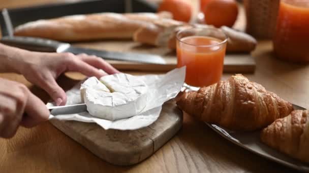 日当たりの良いキッチンでクロワッサンとフランスの朝食のための女の子の手カットブリー おいしいパン屋さんのペストリーと健康的な朝の食事のためのキャンベル — ストック動画