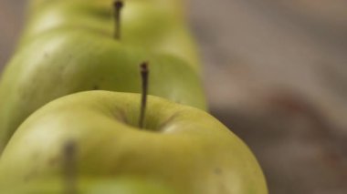 Tahta masaya uzanmış yeşil sulu elmalar, kapatın.