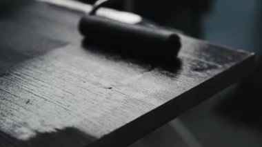 Black color painting surface of wooden table using roller brush. House and furniture renovation.
