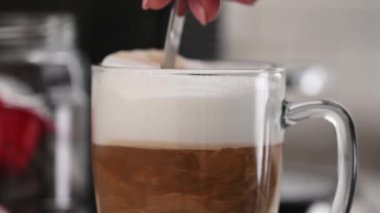 Şeffaf fincanda karıştırılmış kahve kapuçinosu, yakın görüş.