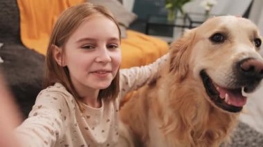 Golden Retriever köpekli küçük kız sosyal medya için video bloğu içeriği kaydediyor. Köpek besleyen güzel çocuk blog videosu yapıyor.