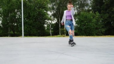 Kız patenci şehir parkında rampada kayıyor ve paten kaymayı seviyor. Aktif boş zamanlarında ve paten kayarken genç bir kız.