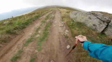 Dağlardaki patikada yürüyüş sopasıyla gezen bir turist, ilginç bir bakış açısı.