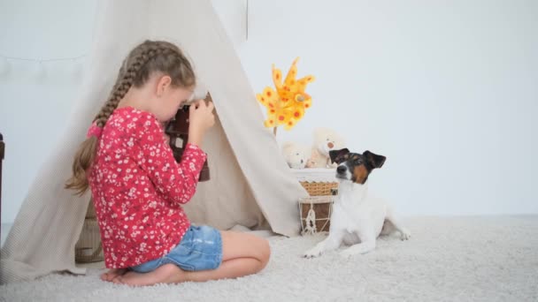 女の子子供撮影キツネテリア犬とともにフィルムカメラで遊び部屋 — ストック動画