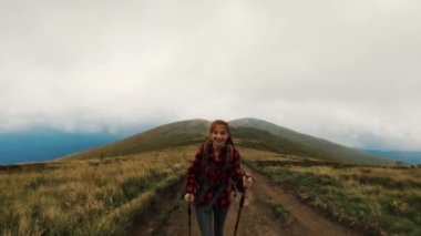 Dağlarda yürüyüş sopalarıyla gezen genç bir turist kız.