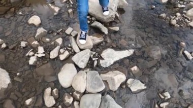 Küçük çocuk taş yoldan nehri geçti.