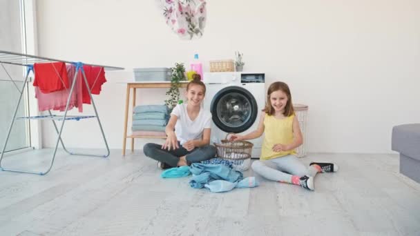 Szczęśliwe Siostry Rzucając Ubrania Kamery Podczas Siedzenia Podłodze Łazience Obok — Wideo stockowe