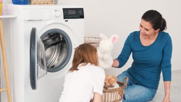 洗濯室で洗濯機にぬいぐるみをロード母と娘 — ストック動画