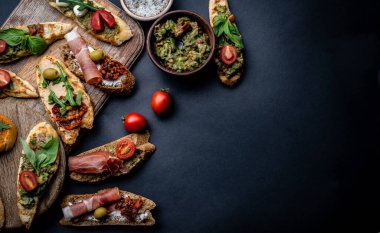 Jambon, zeytin, pesto, domates, fesleğen ve mozzarella soslu bruschetta seti tahtadan yapılmış guacamole ve kirazlı. Fotokopi alanına sahip geleneksel Akdeniz yemek bileşimi