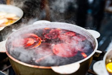 Noel zamanı, sokak yemekleri pazarındaki çömleklerde sıcak meyve suyu şarabı. Açık hava festivalinde renkli şenlikli sıcak içecekler.