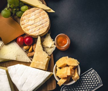 Different kinds of cheese served with wine bottle, glasses and grape for gourmet nutrition. Organic parmesan and brie set with alcohol composition