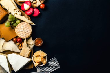 Different kinds of cheese served with wine bottle, glasses and grape for gourmet nutrition. Organic parmesan and brie set with alcohol composition
