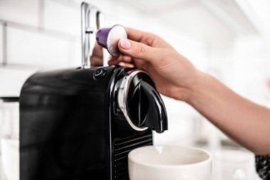 Girl hand put capsule to coffee machine at home closeup. Woman preparing italian caffeine beverage using professional espresso maker