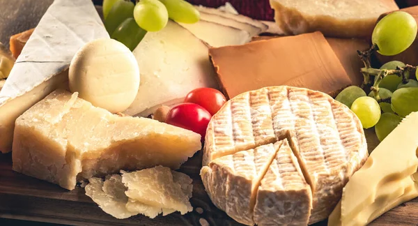パルメザンチーズやさまざまな種類のチーズは ブドウの蜂蜜のクローズアップで提供しています 有機ブリーとキャンバーセットのデリカテッセンコレクション — ストック写真