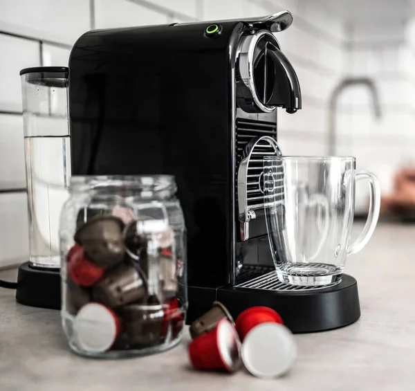 家庭厨房的咖啡机 装有胶囊和透明的杯子 浓缩咖啡 咖啡因饮料制造商和现代杯子 — 图库照片