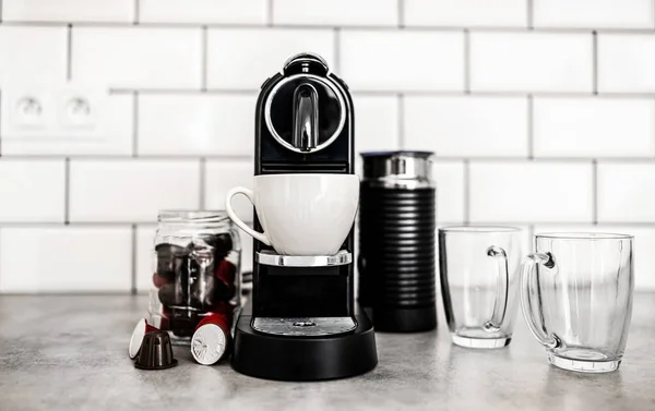 家庭厨房里有不同胶囊和透明杯子的咖啡机 浓缩咖啡 咖啡因饮料制造商和现代杯子 — 图库照片