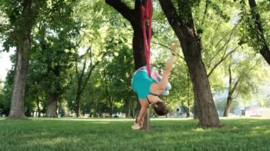 Açık havada yoga yaparken hamaklı genç bir kız. Parkta havadan esneme hareketleri yapan bir kadın.