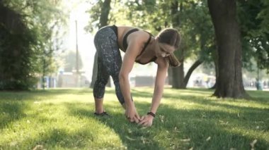 Yoga yapan ve sabahları vücudunu esneten genç bir kız. Dışarıda egzersiz yapan bir kadın.
