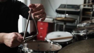 Man hand playing on music triangle beating with metal stick and waiting sound. Musician with traditional instrument in recording studio