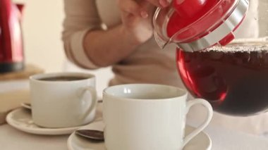 Mutfakta fincana cam çaydanlıktan sıcak siyah çay dökülüyor.