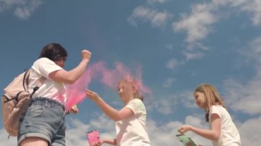 Holi Festivali 'nde kızları olan bir anne Holi tozuyla oynuyor, renkli bir toz fırlatıyor.