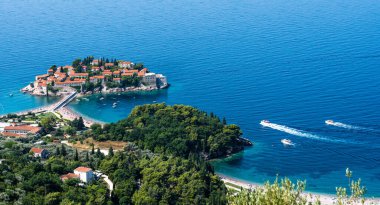 Karadağ 'daki Sveti Stefan adası ve yukarıdaki orman. Akdeniz kıyısındaki Adriyatik denizi ve lüks tatil köyünün manzarası