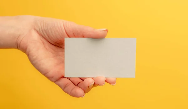白色名片 女性手中有复制空间 背景为黄色 供联系信息和演示用的标识空白 — 图库照片